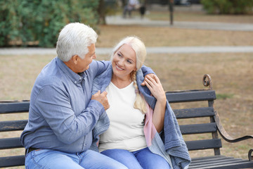 Poster - Mature couple sitting on bench outdoors