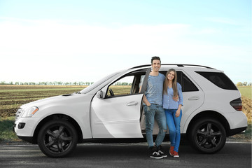 Poster - Beautiful young couple standing near car outdoors