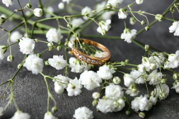 Wall Mural - Beautiful engagement ring and flower on gray table, closeup