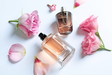 Wall Mural - Bottles of perfume with flowers on light background