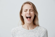 Emotional Blonde Woman Opening Her Mouth Widely Screaming Loudly Being Dissatisfied With Something Expressing Disagreement And Annoyance. Female Shouting At Boyfriend, Negative Emotions And Feelings