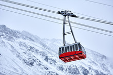 Red Cable Car In The Background Of The Winter Mountains.  Old Red Cable Car At Mountain. Ski Resort Maso Corto, Italy, Trentino Alto Adige.  Red Cable Car In The Mountains In Winter