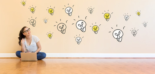 Wall Mural - Light Bulbs with young woman using a laptop computer on floor