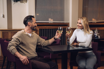 beautiful happy middle aged couple drinking wine and smiling each other in hotel restaurant