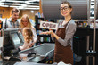 Portrait of happy woman cashier holding open sign