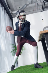 Wall Mural - angry businessman in rugby helmet playing american football in office