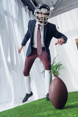 Wall Mural - businessman in rugby helmet playing american football in office