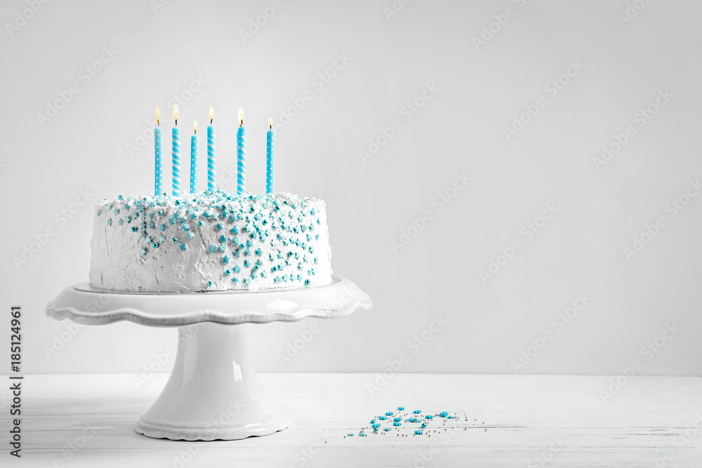 Stand with birthday cake and candles on table against light wall Stock ...