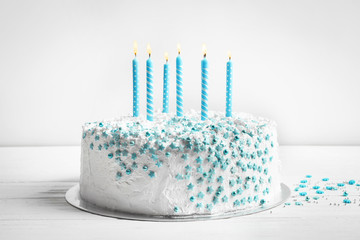 Canvas Print - Birthday cake with candles on table against light wall