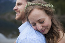 Girlfriend With Eyes Closed Wearing Wreath While Embracing Boyfriend At Lakeshore
