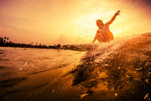Young Surfer Rides The Wave During Sunset
