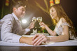 © Anucha - Asian couple holding hands together and cheering glasses of wine. Focus at hand and ring.