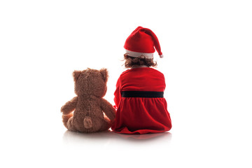 Wall Mural - Little girl in red chrismas santa hat and her teddy bear friend toy on white background