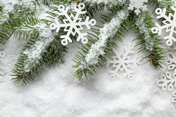 Christmas background - snowflakes and spruce tree on white snow