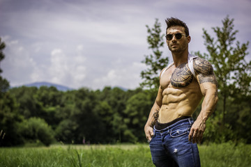 Wall Mural - Handsome Muscular Shirtless Hunk Man Outdoor in City Park Standing on Grass. Showing Healthy Muscle Body While Looking away