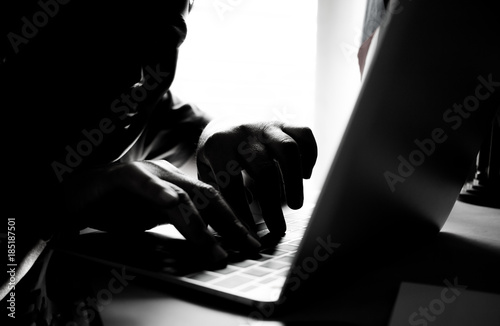 Fotomural Hackers with black mask using hands of anonymous typing code on keyboard of lapt