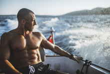 Muscular Shirtless Man Sitting In Motorboat
