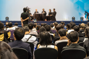 Speakers on the stage with Rear view of Audience in the conference hall or seminar meeting, business and education about investment concept