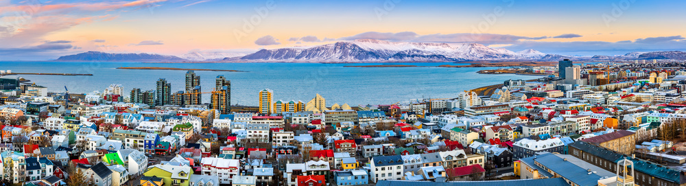 Aerial panorama of downtown Reykjavik at sunset with colorful houses and snowy mountains in the background - obrazy, fototapety, plakaty 