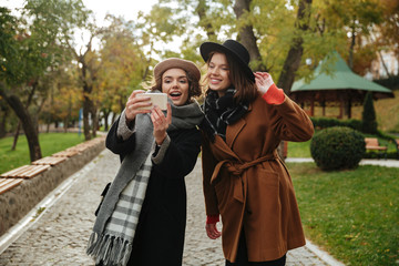 Wall Mural - Portrait of two cheerful girls dressed in autumn clothes