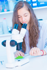 Poster - schoolgirl in a class of biology is studying a green plant