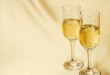 two glasses of champagne on a background of a fabric of golden color