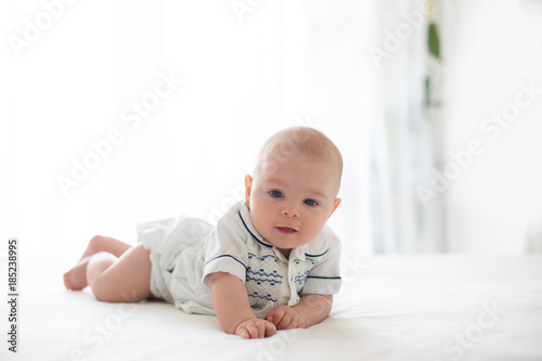 Fototapeta Cute little four month old baby boy, playing at home in bed
