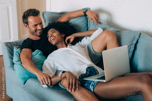 Happy Young Couple Relaxed At Home Lying Down In The Couch On The