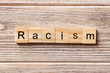 Racism word written on wood block. Racism text on table, concept