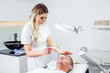 © Helga Bragina - Cosmetologist woman is doing eyebrow modeling for man by wax for epilation. Cosmetological clinic. Healthcare