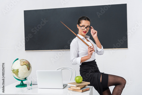 Young Sexy Teacher In Stockings With Pointer Sitting On Desk In Front 