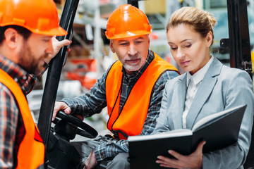 Wall Mural - two workers and inspector using forklift machine in storehouse