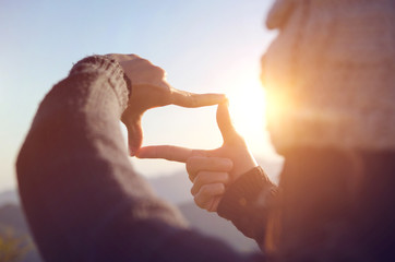 close up of woman hands making frame gesture with sunrise on moutain, female capturing the sunrise, 