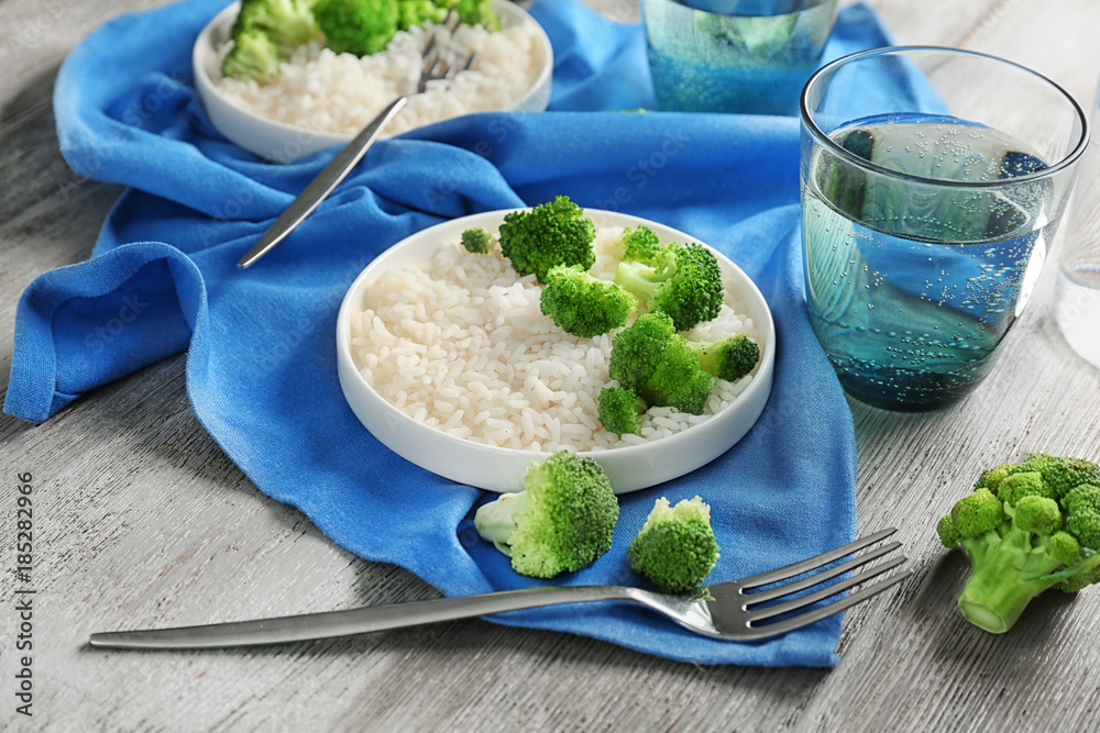 Plate with rice and broccoli on wooden table