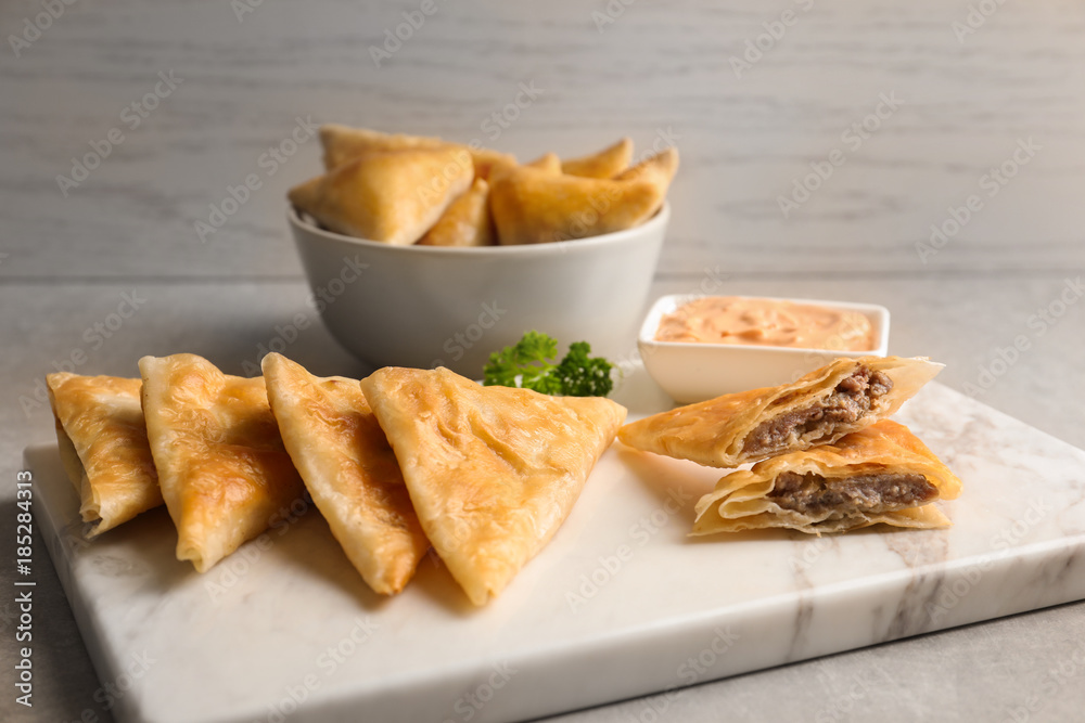 Board with delicious meat samosas on table