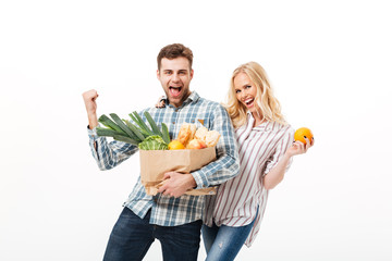 Wall Mural - Portrait of a cheerful couple holding paper shopping bag