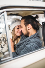 Handsome hipster Man and beauty woman kiss each other sitting in the retro car . Valintine's Day concept. Vertical picture