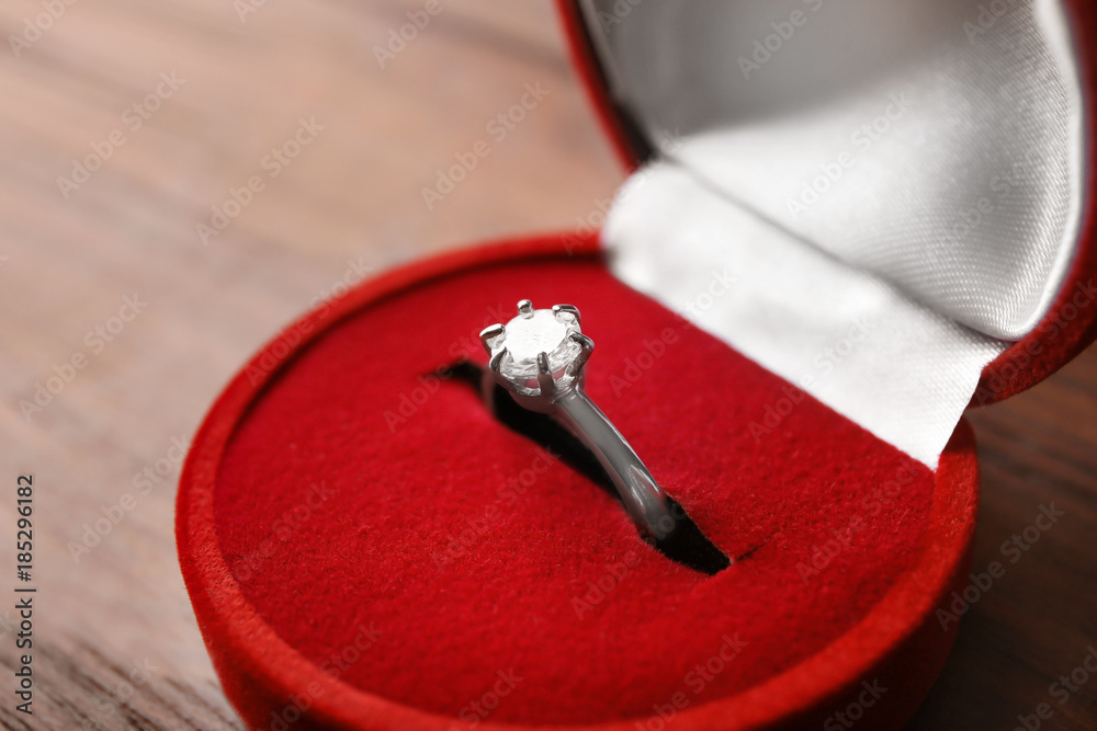 Box with luxury engagement ring on wooden background, closeup