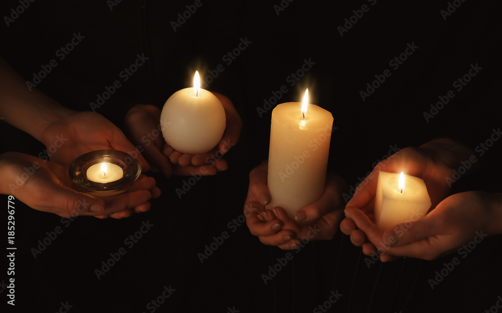 Hands with burning candles on dark background