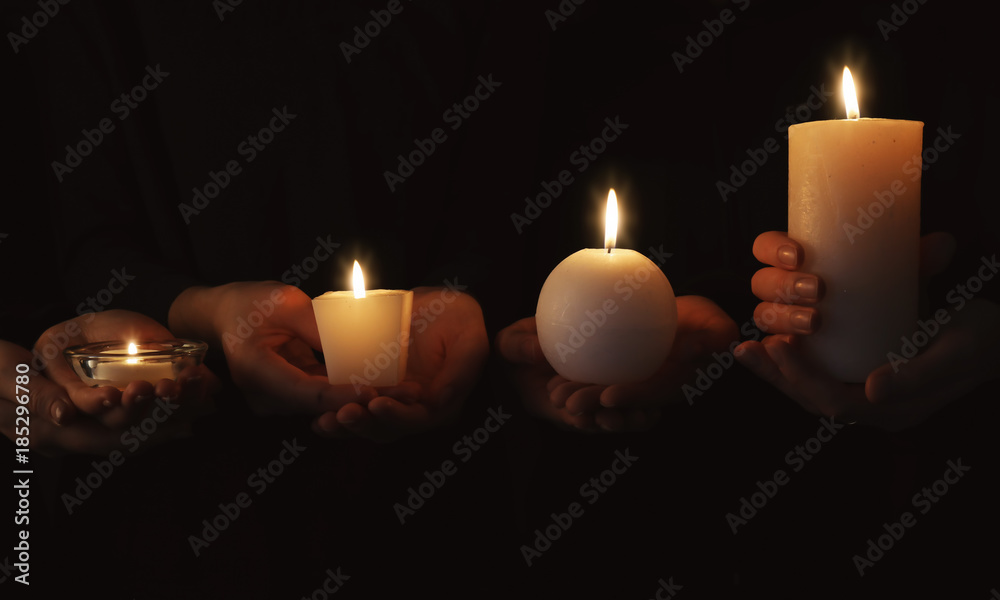 Hands with burning candles on dark background