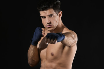 Wall Mural - Attractive young boxer on black background