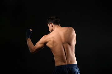 Wall Mural - Attractive young boxer on black background