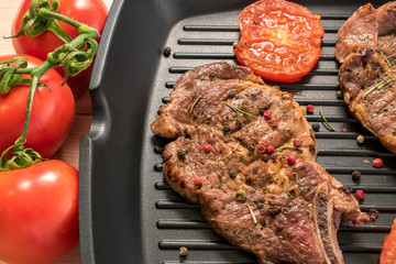 Grilled steak on grill pan with tomatoes and spices close-up