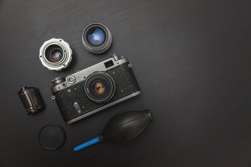 Canvas Print - Vintage Film Camera And Accessories On Black Wooden Background Technology Development Concept. Top View