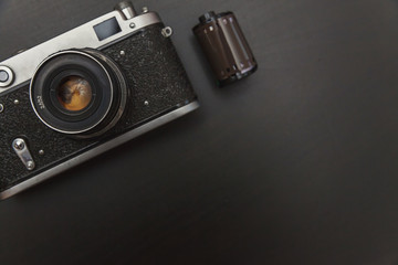 Wall Mural - Vintage Film Camera And Roll On Black Wooden Background Technology Development Photographer Concept with copy space. Top View