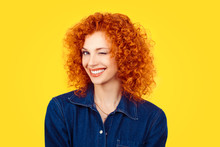 Winking. Closeup Woman Redhead Curly Hair Smiling Blinking Eye To You Camera Isolated On Yellow Background. Happy Life Pictures, Happiness