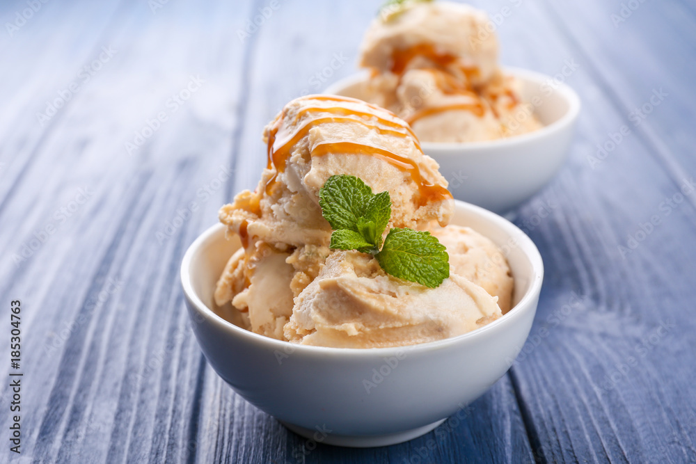 Delicious ice cream with caramel syrup in bowl on table