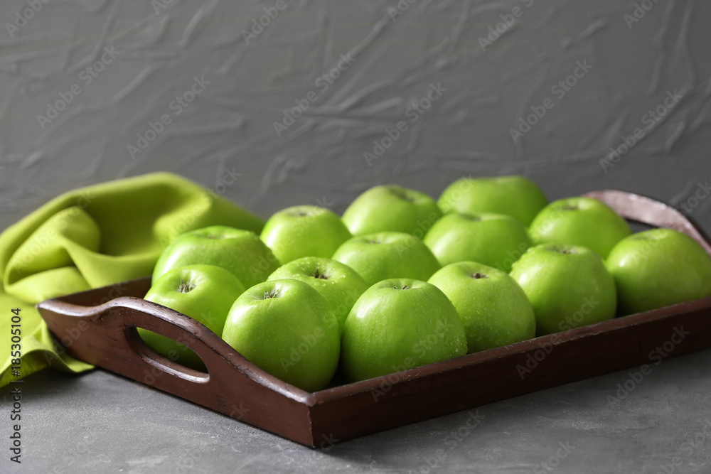 Tray with fresh green apples on grey background