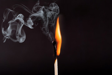 Matches stick with the flame and smoke burning, isolated on a black background