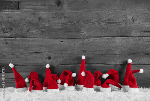 Cuadros en Lienzo Humorously red, grey and white wooden christmas background with santa hats